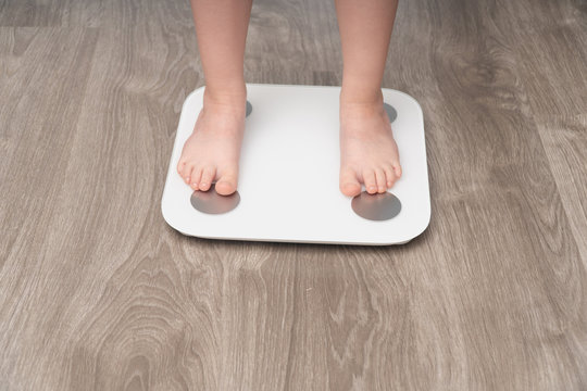 close-up of the feet of a child who is standing on the scales. Baby weight control concept