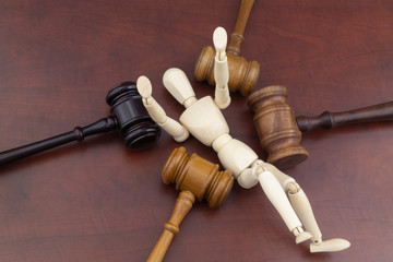 Many laws affect a person concept. Wooden mannequin and four judge gavels.