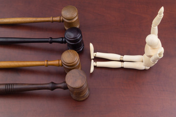 Man surrenders to many laws. Judges gavels and wooden mannequin.