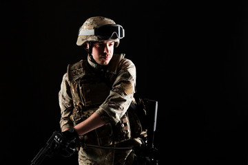 Fototapeta premium Soldier with gun is on mission on black background. Concept of war.