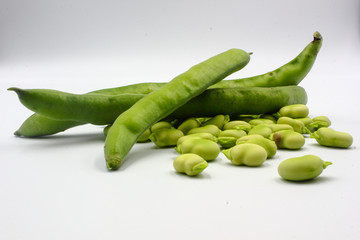  open green broad beans in their shells and some shelled beans isolated on a white background