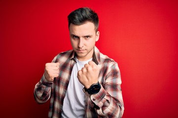 Young handsome caucasian man wearing casual modern shirt over red isolated background Ready to fight with fist defense gesture, angry and upset face, afraid of problem