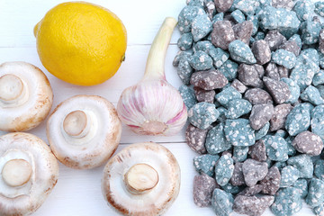 Mushrooms, garlic and lemon on a white wooden background. Stones, blue and red granite