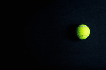 Single tennis ball on a black background
