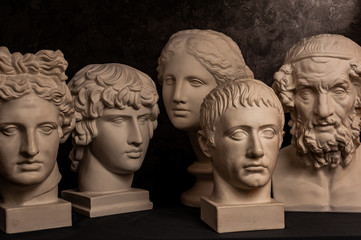 Group gypsum busts of ancient statues human heads for artists on a dark background. Plaster...