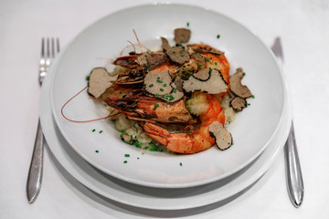 Black truffle slices shaved on top of a plate of grilled prawn risotto served at a luxury restaurant in Nice, France