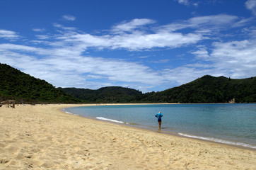 A woman with her feet in the sea of abel tasman beach.