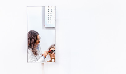 Doctor and patient in ophthalmology clinic doing eye examination, reflection in the mirror
