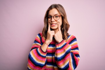 Young beautiful blonde girl wearing glasses and casual sweater over pink isolated background Smiling with open mouth, fingers pointing and forcing cheerful smile
