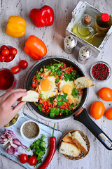 Fried eggs in a pan with stewed vegetables and herbs, close-up. Rustic breakfast