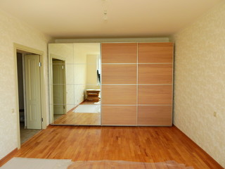 Flat pack furniture wardrobe with a mirror installed wall to wall in a small apartment room