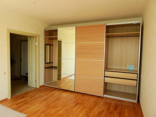 Fototapeta na wymiar Flat pack furniture wardrobe with a mirror installed wall to wall in a small apartment room