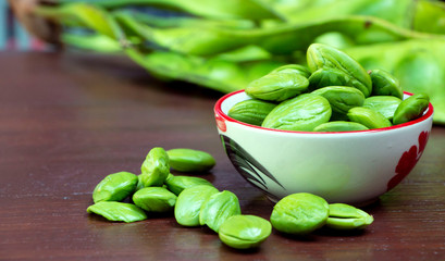 Bitter bean seeds(Parkia speciosa)  in a bowl and on a wooden table. Solving the symptoms of kidney disorders.