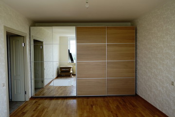 Flat pack furniture wardrobe with a mirror installed wall to wall in a small apartment room
