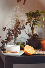 Slow living concept. Cozy area for relaxing and rest with cup of hot tea or coffee, fresh orange...