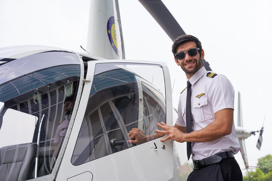 Handsome Pilot Smiling While Opening the Door of the Helicopter.