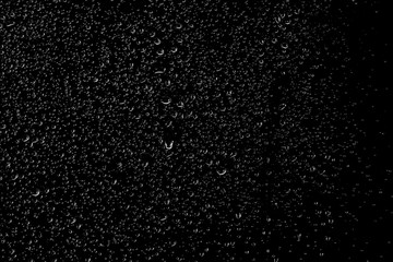 Obraz premium Drops of water flow down the surface of the clear glass on a black background. 