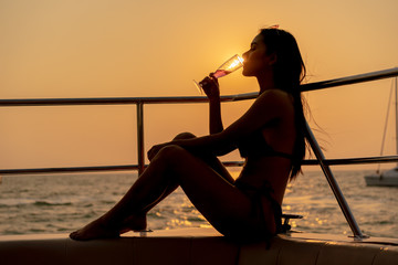 Fototapeta na wymiar Sexy Asian Women in Bikini Drinking Glasses of Champagne or Wine on a yacht.