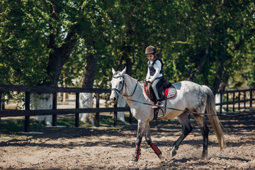 Little Girl in helmet Learning Horseback Riding. Instructor teaches kid Equestrian.