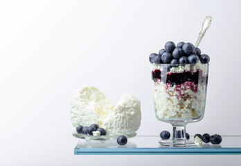 Cottage cheese with blueberry jam and fresh berries on a white background.