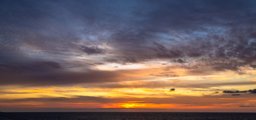 Obraz premium Sunset and dramatic set of clouds drifting over the tropical waters of the Caribbean Sea are lit by the last moments of daylight.