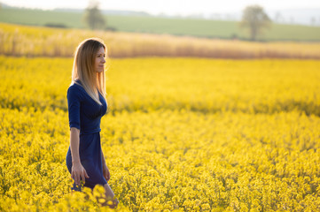 Fototapeta premium Beautiful blonde model in rapeseed field