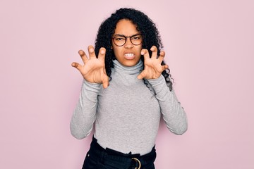 Young african american woman wearing turtleneck sweater and glasses over pink background smiling...
