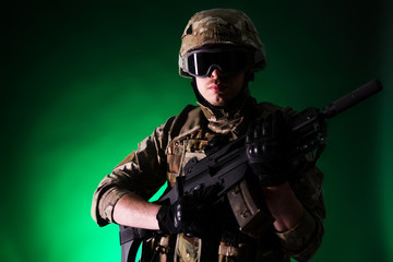 Soldier with gun is on mission on green background. Concept of war.