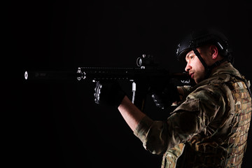 Soldier with gun is looking through the scope on violet background. Concept of war. Veterans,...