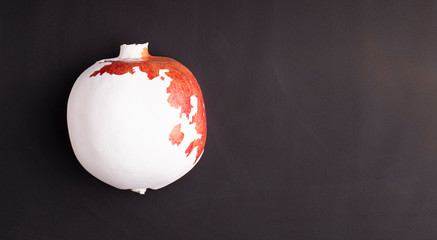 Red pomegranate with white paint on black background