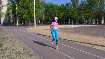 Sporty fitness girl running marathon on empty stadium.Runner young beautiful woman in process of loosing weight  warm up on stadium.Active life and sport concept