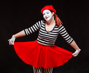 Portrait of female mime artist performing, isolated on black background. Woman in striped clothes...