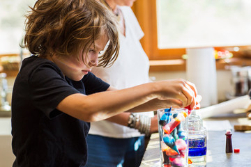 6 year old boy in kitchen with his mother, doing science experiment