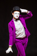 Portrait of male mime artist, isolated on black background. Man in a purple suit is happily posing...