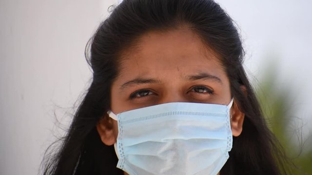 Indian teenage girl wearing medical mask turning her head and staring at the camera during the Coronavirus pandemic