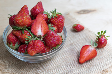 Strawberries in a glass plate on a wooden background. Strawberry season.