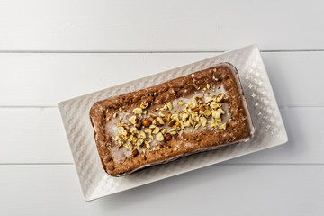 Banana loaf cake with nuts on top wooden table top view.