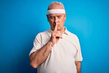 Middle age hoary sportsman doing sport wearing sportswear over isolated blue background asking to be quiet with finger on lips. Silence and secret concept.