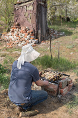 a man in a hat by the fire with meat. A festive holiday. Delicious meat on a picnic