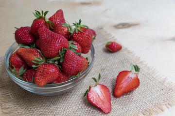 Strawberries in a glass plate on a wooden background. Strawberry season.