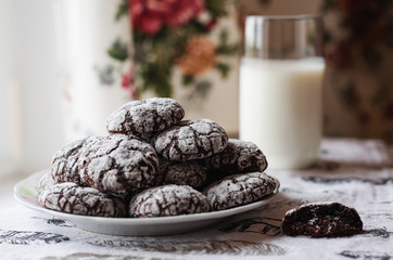 Homemade chocolate cookies with powdered sugar and glass of milk at the kitchen.