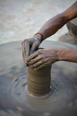 Hands working on pottery wheel and making a pot