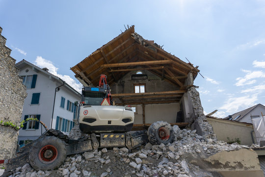 abandoned house being demolished with mobile walking excavator and rubble and rocks