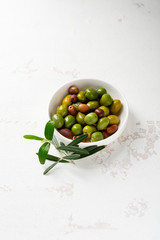 Close up of green pickled olive in white bowl