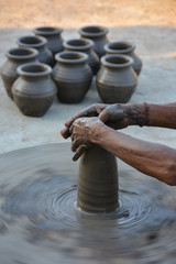 Hands working on pottery wheel and making a pot