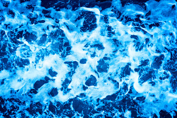 Aerial Ocean water surface with foam and waves behind of fast moving powerful engines.