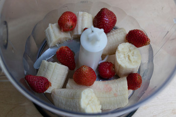 Banana and strawberries in a blender bowl are ready to mix. Tasty drink. Yummy.