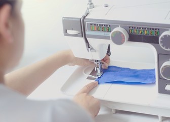 Woman using sewing machine to make medical mask during pandemic and quarantine.