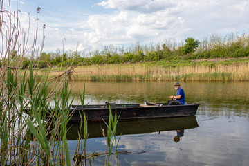 Naklejka premium Senior fisherman in a boat at Danube-Tisa-Danube channel near Novi Sad, Serbia.