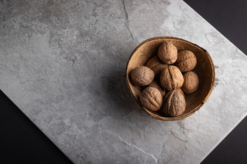 Walnuts inside a coconut shell on a tile background